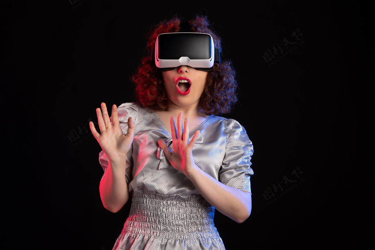 现实美丽的女性戴着虚拟现实耳机在黑暗的表面女人人视觉