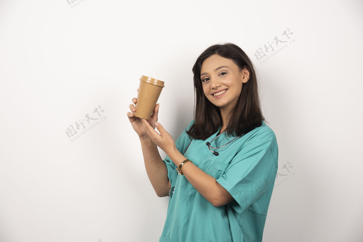 工作女医生拿着一杯白色背景的咖啡高质量的照片阳性听诊器职业
