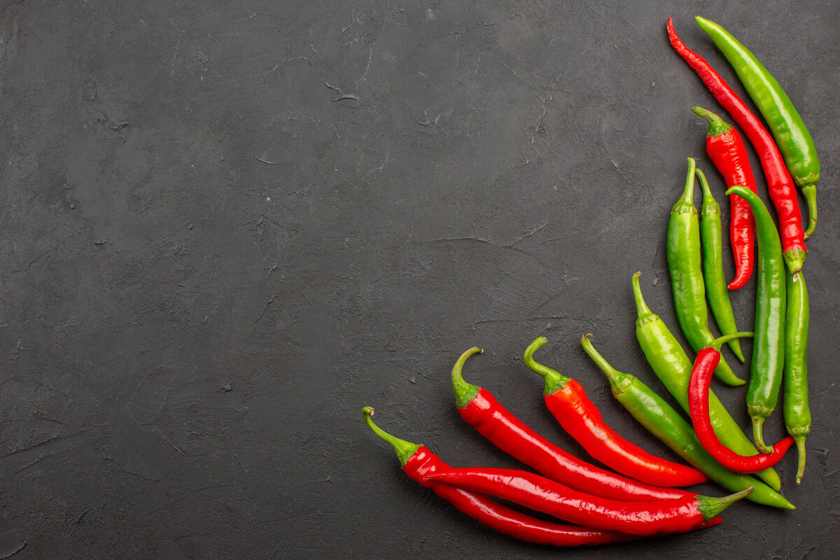 蔬菜顶视图红色和绿色的辣椒在黑色桌子的右下角与自由空间辣椒胡椒热量