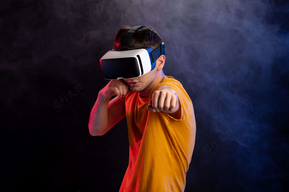 人帅哥戴着虚拟现实耳机在黑暗的表面游戏玩人