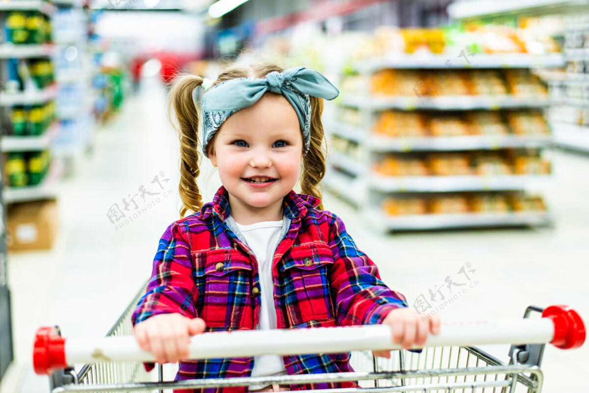 买有趣的小女孩 坐在手推车在超市购物的家庭孩子女孩购物车