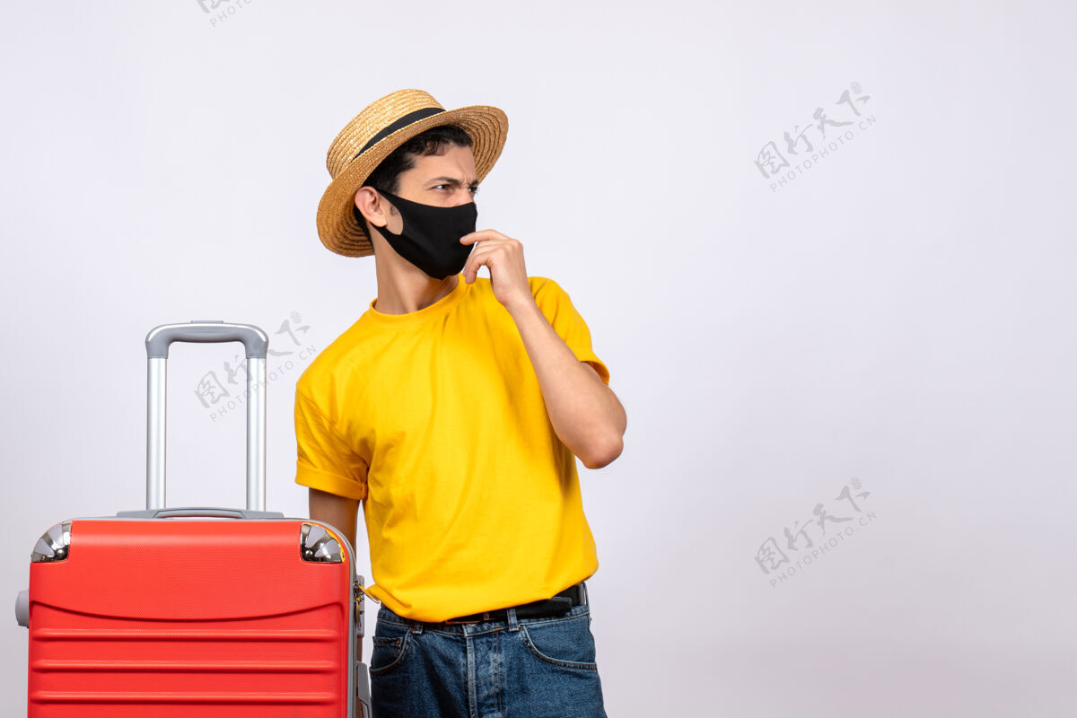 人前视图：穿着黄色t恤和红色手提箱的年轻人在看什么东西手提箱成人前面