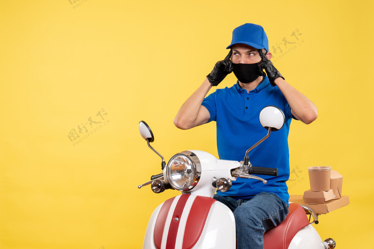 视图正面图黄色背景上身穿蓝色制服的年轻男性信使-流感病毒自行车工作递送传送带男性摩托车