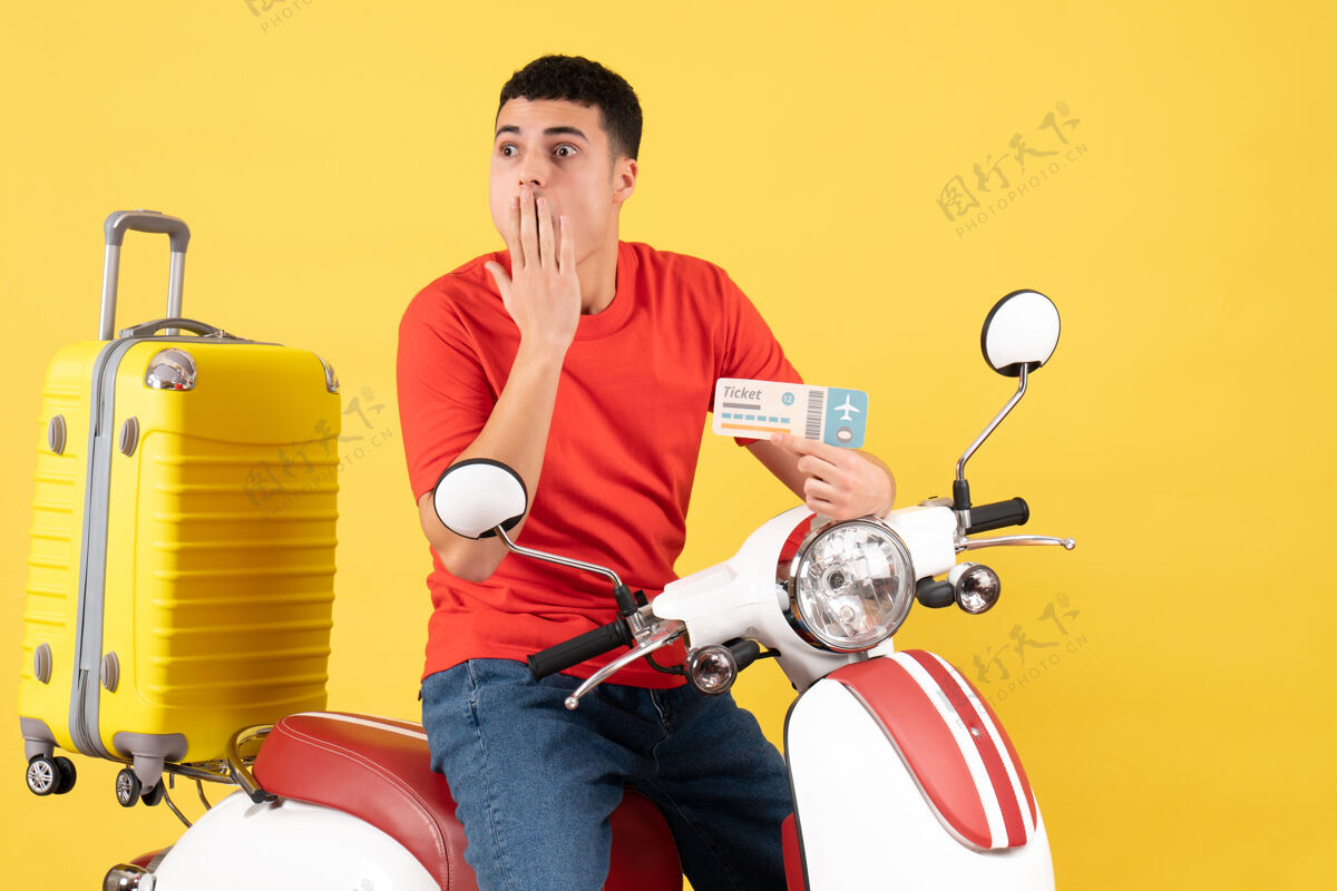 主动正面图：一个穿着便服的年轻男子拿着车票坐在轻便摩托车上男持有视图