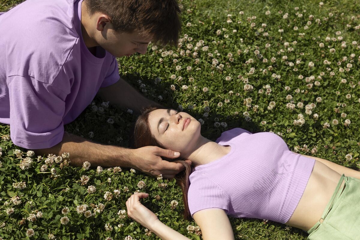舒适可爱的男女朋友躺在草地上快乐男人年轻