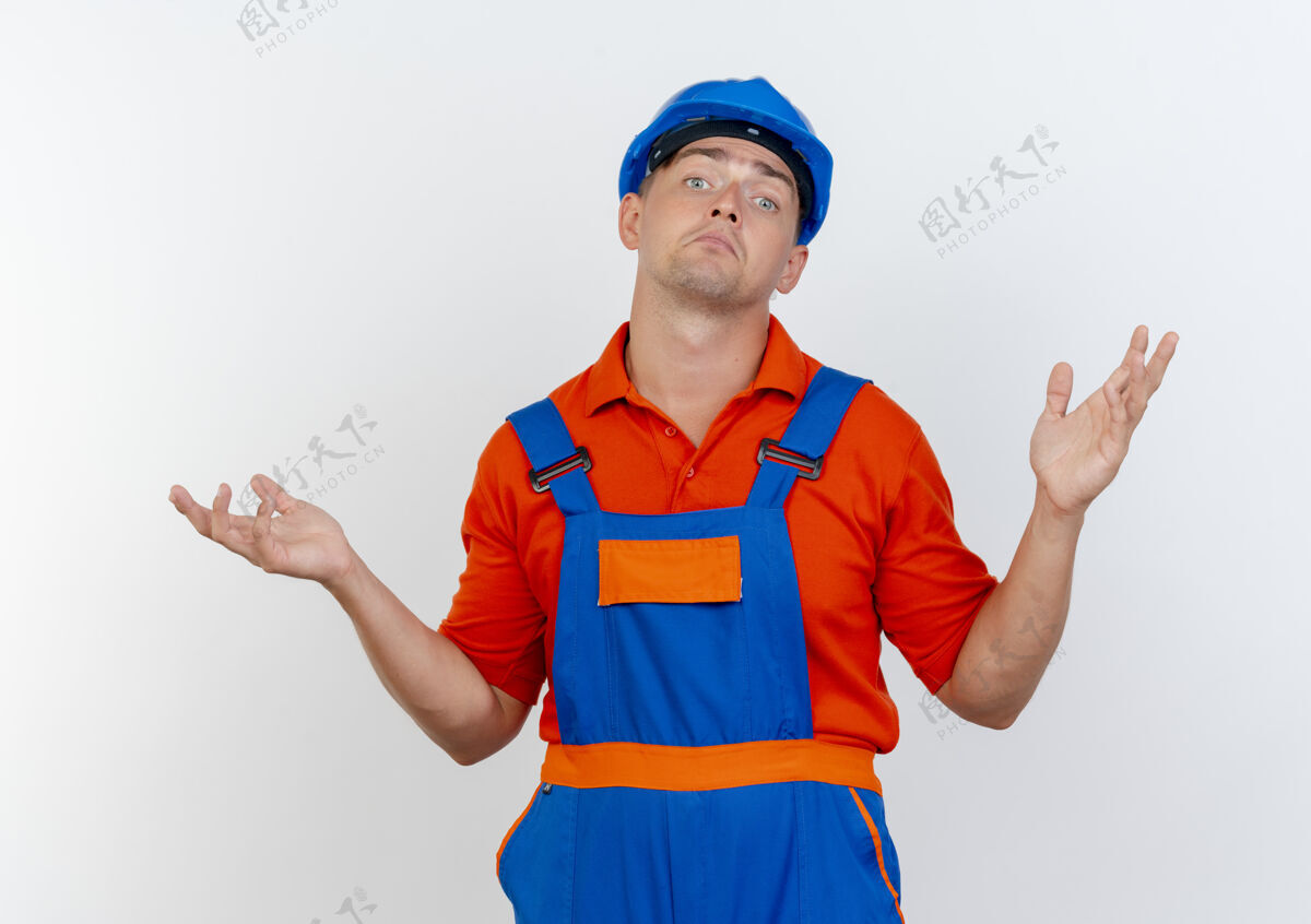 年轻困惑的年轻男性建筑工人穿着制服和安全帽摊开双手背景建筑商安全