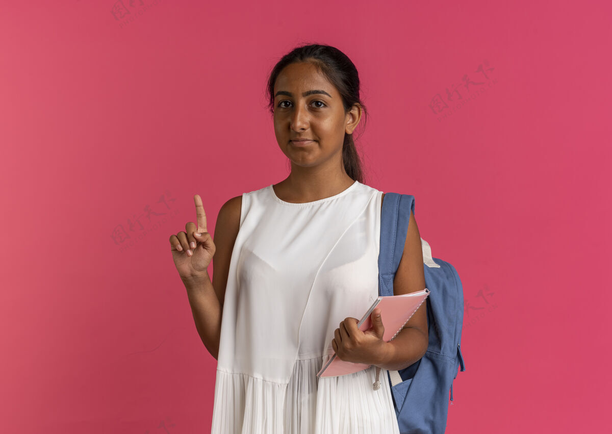 笔记本高兴的小女生背着书包拿着笔记本 指着上面拿着请粉色