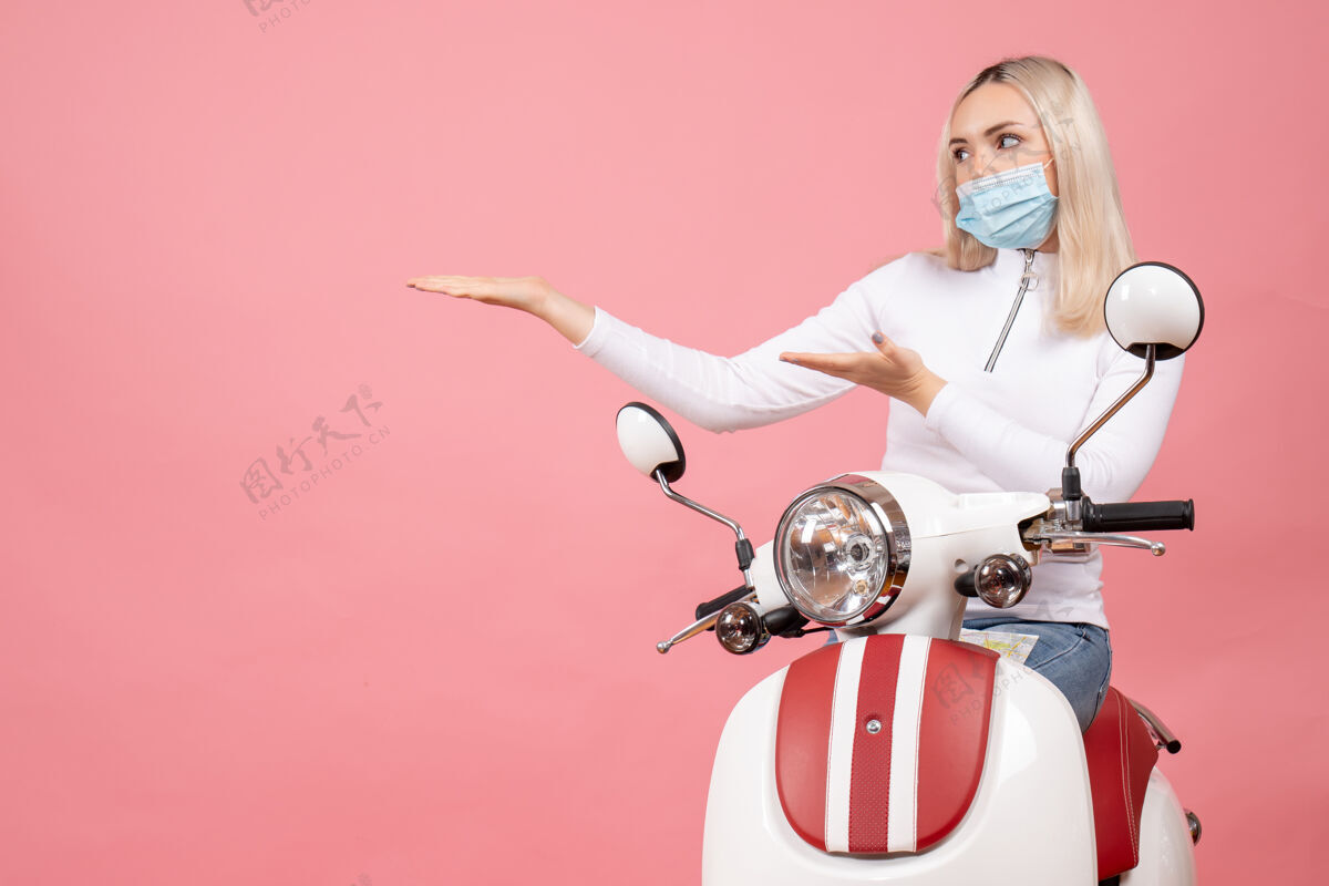 传送带正面图：戴着面具的年轻女士站在轻便摩托车旁边轻便摩托车前面时尚