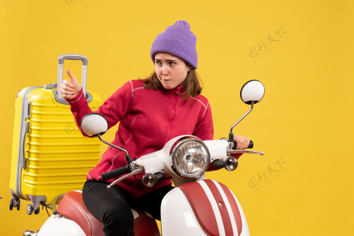 前面前视图：骑着轻便摩托车的年轻女孩正在做竖起大拇指的招牌车辆拇指摩托车