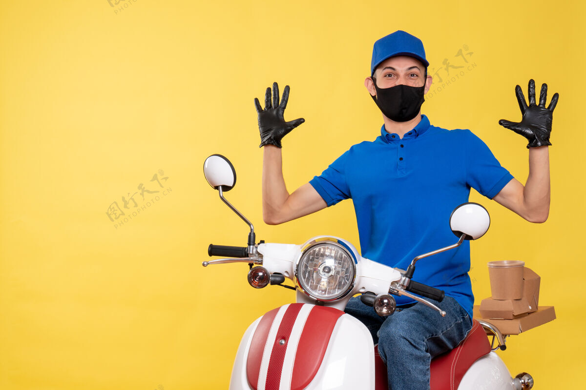 送货前视图年轻的男性信使在蓝色制服和面具上的黄色背景工作视图病毒