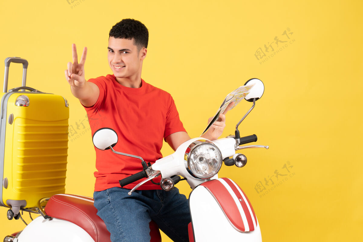 轻便摩托车前视图骑着轻便摩托车的年轻人拿着地图在做胜利的标志人摩托车胜利