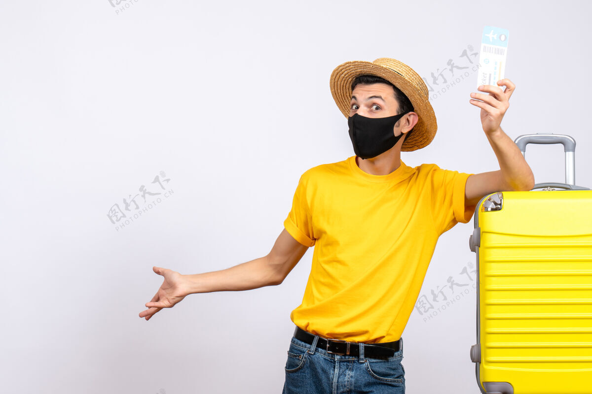 前面正面图穿着黄色t恤的年轻人站在黄色手提箱旁举着机票T恤微笑衬衫