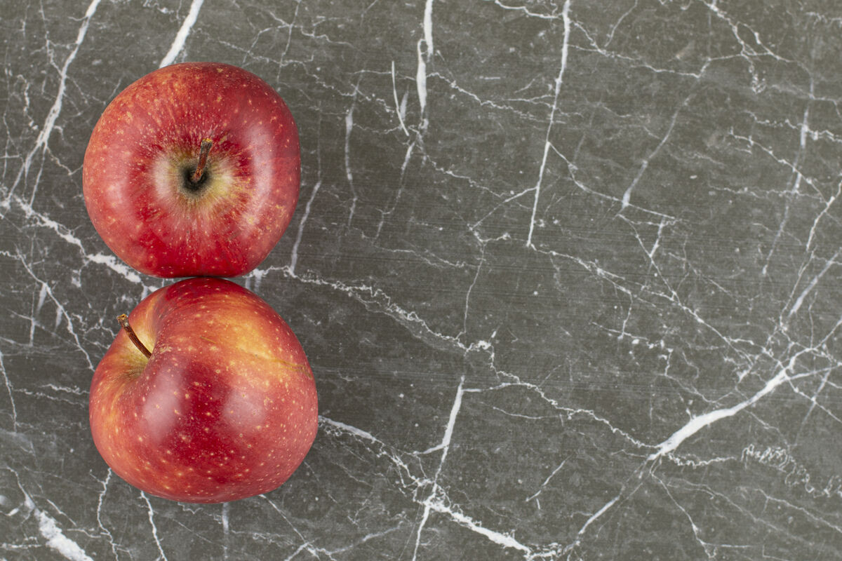 夹两个新鲜的苹果放在灰石头上健康成熟自然