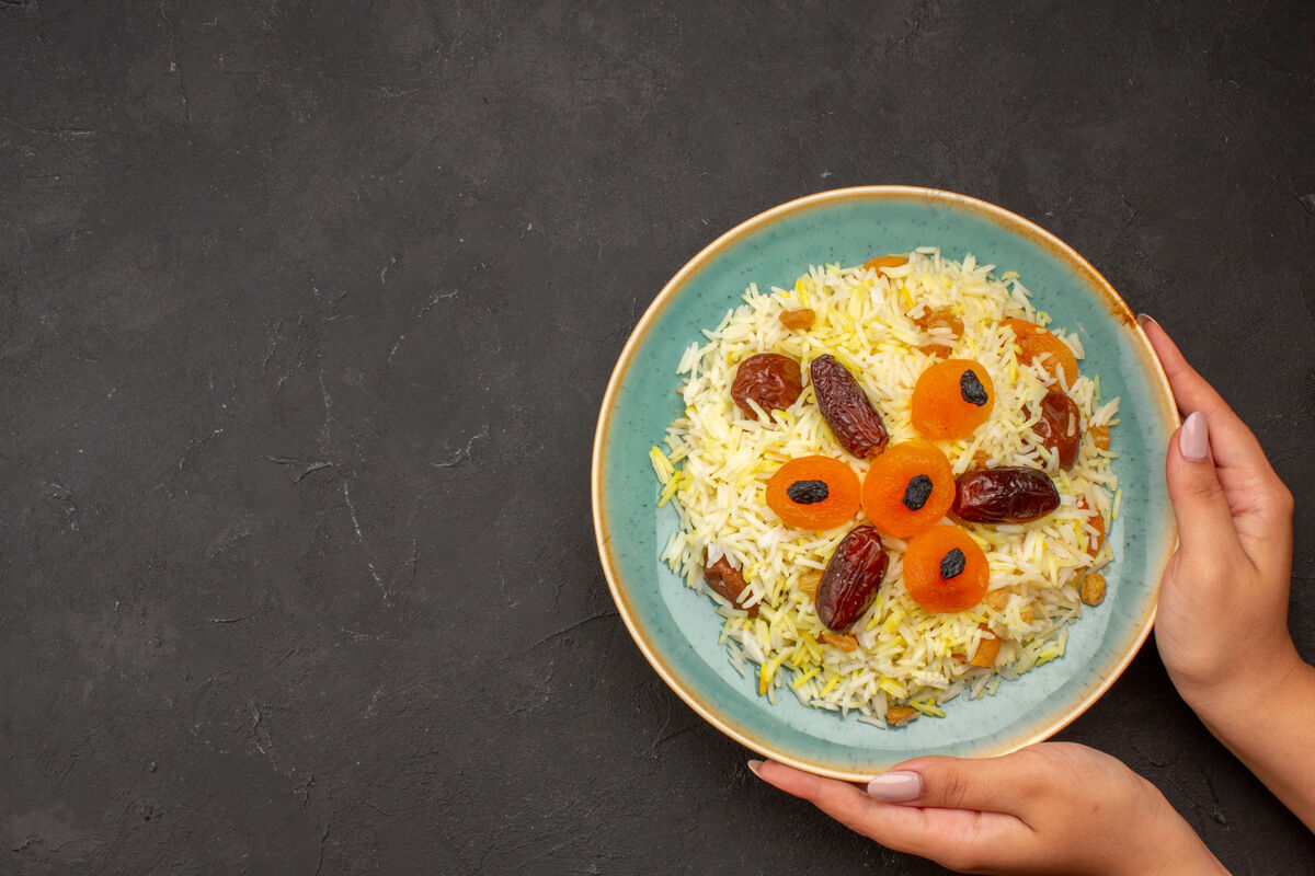 美味美味的煮熟的普洛夫米饭与不同的葡萄干在灰色的表面盘内俯视一餐不同配菜