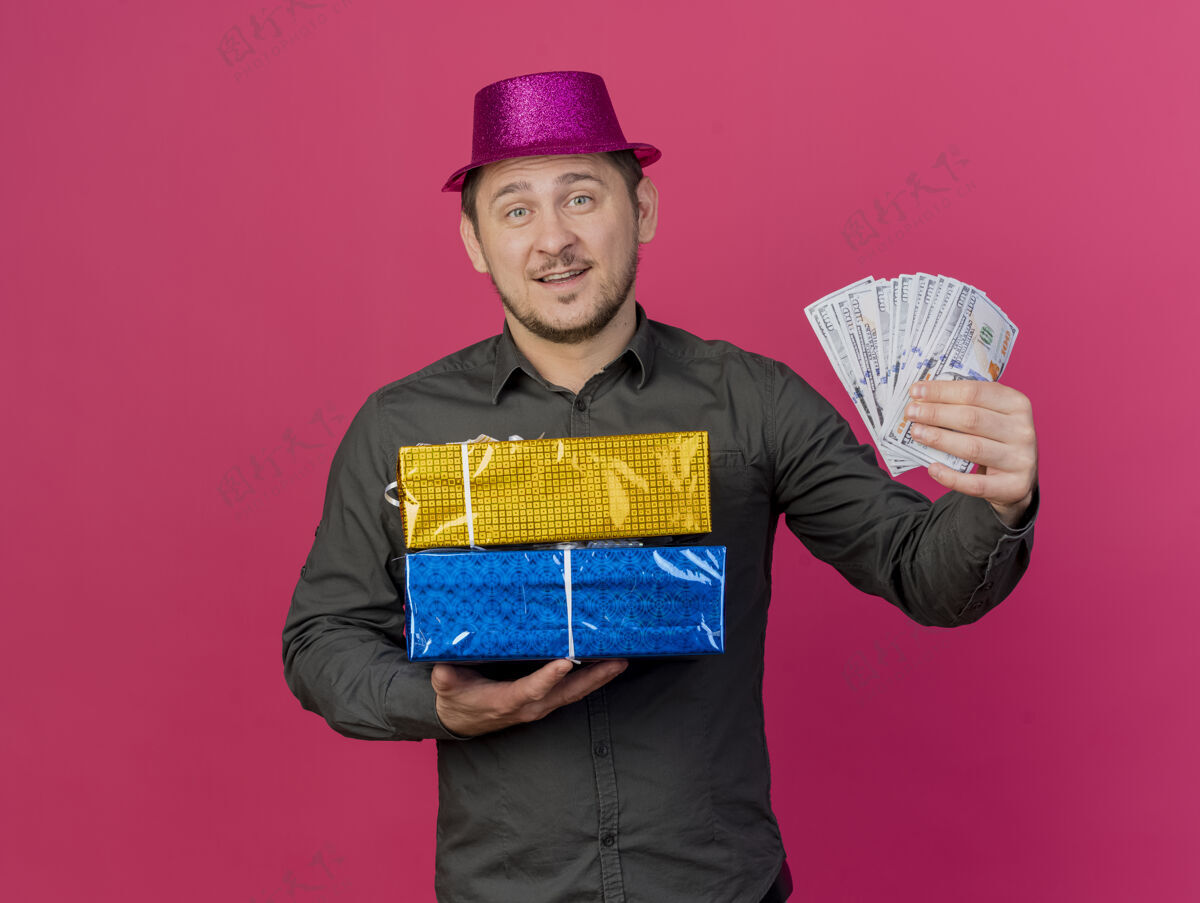礼物微笑着的年轻人戴着粉红色的帽子 手里拿着礼盒 礼盒上的现金是粉红色的年轻人现金粉色