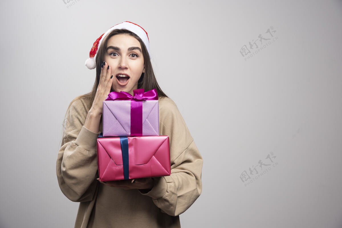 红色拿着两份圣诞礼物的年轻女子表情礼物站着
