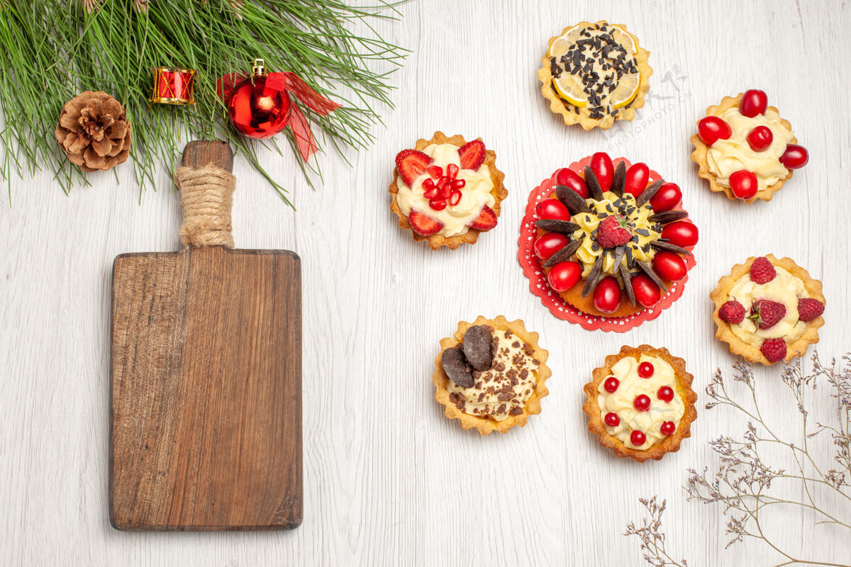 瓢虫顶视图浆果蛋糕圆形馅饼松树树叶与圣诞玩具和砧板上的白色木质地面玩具浆果蛋糕新鲜的