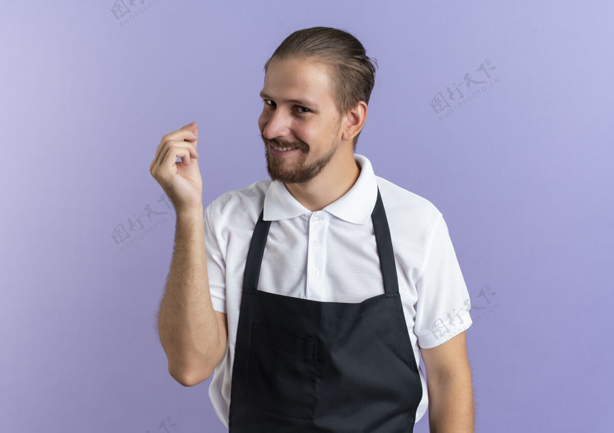 姿势微笑着的年轻帅哥理发师穿着制服做着金钱手势孤立在紫色的墙上衣服微笑帅气