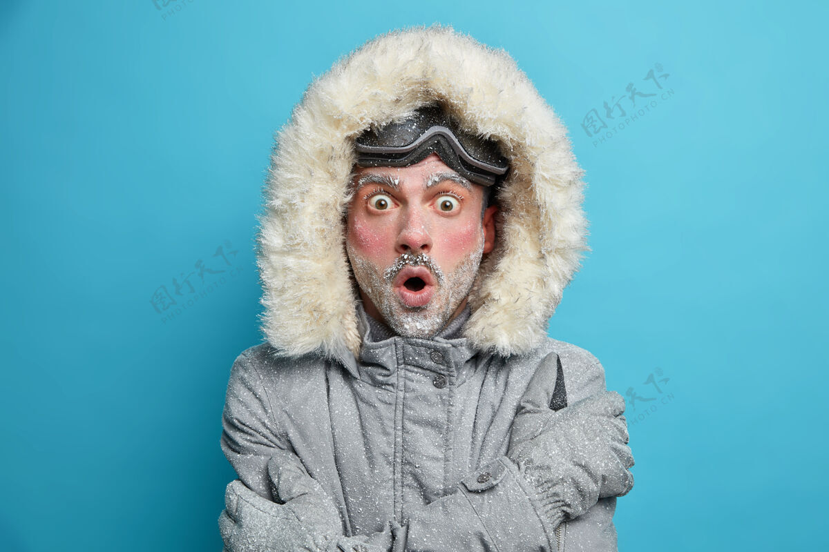 帽子冻得目瞪口呆的红脸男人冻得浑身发抖拥抱自己感受温暖的目光窃听的眼睛戴着滑雪护目镜颤抖凉爽天气