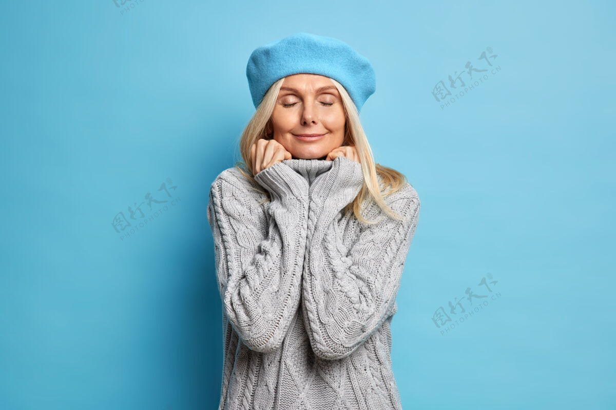 法国高兴的成年女子穿着舒适的针织毛衣双手放在衣领架上闭着眼睛享受宁静的时刻年轻快乐时尚