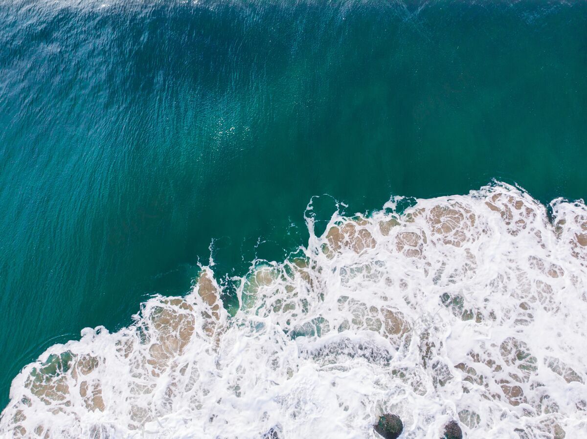 场景头顶空中拍摄的蓝色波浪海-完美的水岩石高