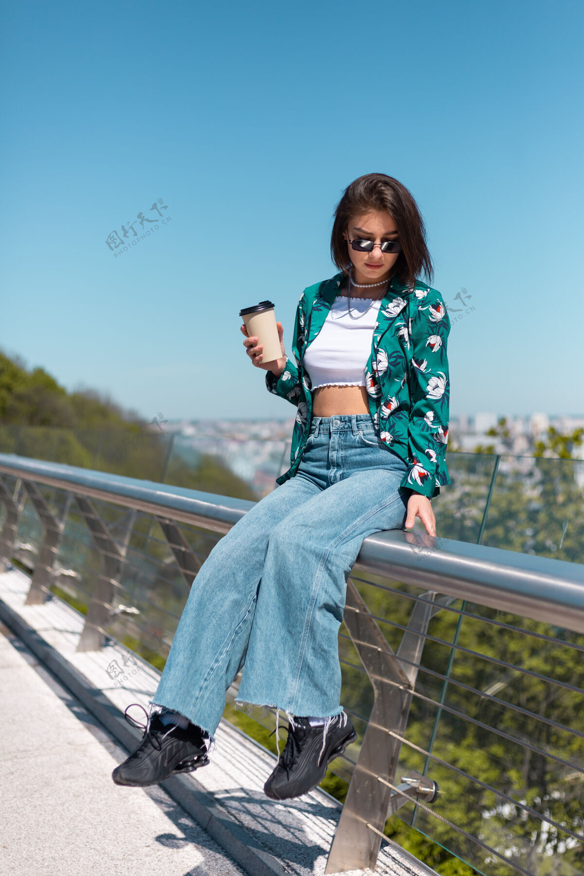 城市户外写真：穿着绿衬衫的女人 喝着咖啡 享受着阳光 站在桥上 清晨的城市景色令人惊叹女士茶深色头发