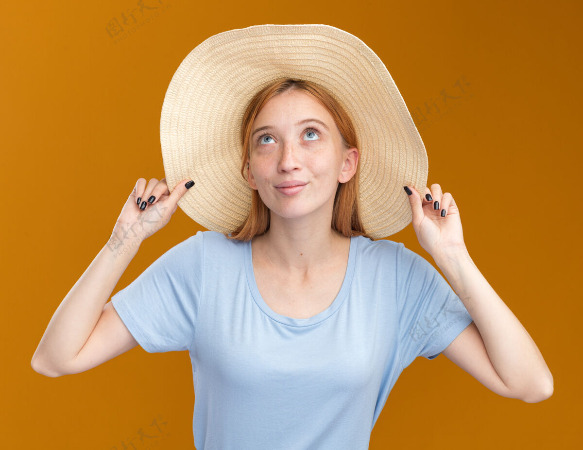 请戴着沙滩帽 满脸雀斑的年轻红发姜黄色女孩高兴地看着橙色帽子穿年轻