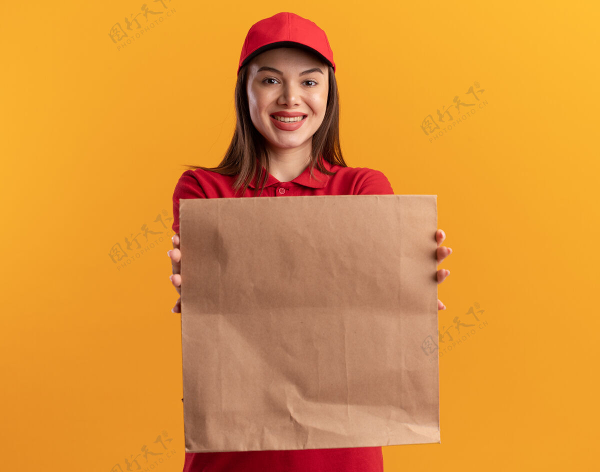 包装微笑着的漂亮送货员穿着制服 在橙色的纸包上伸展纸送货漂亮