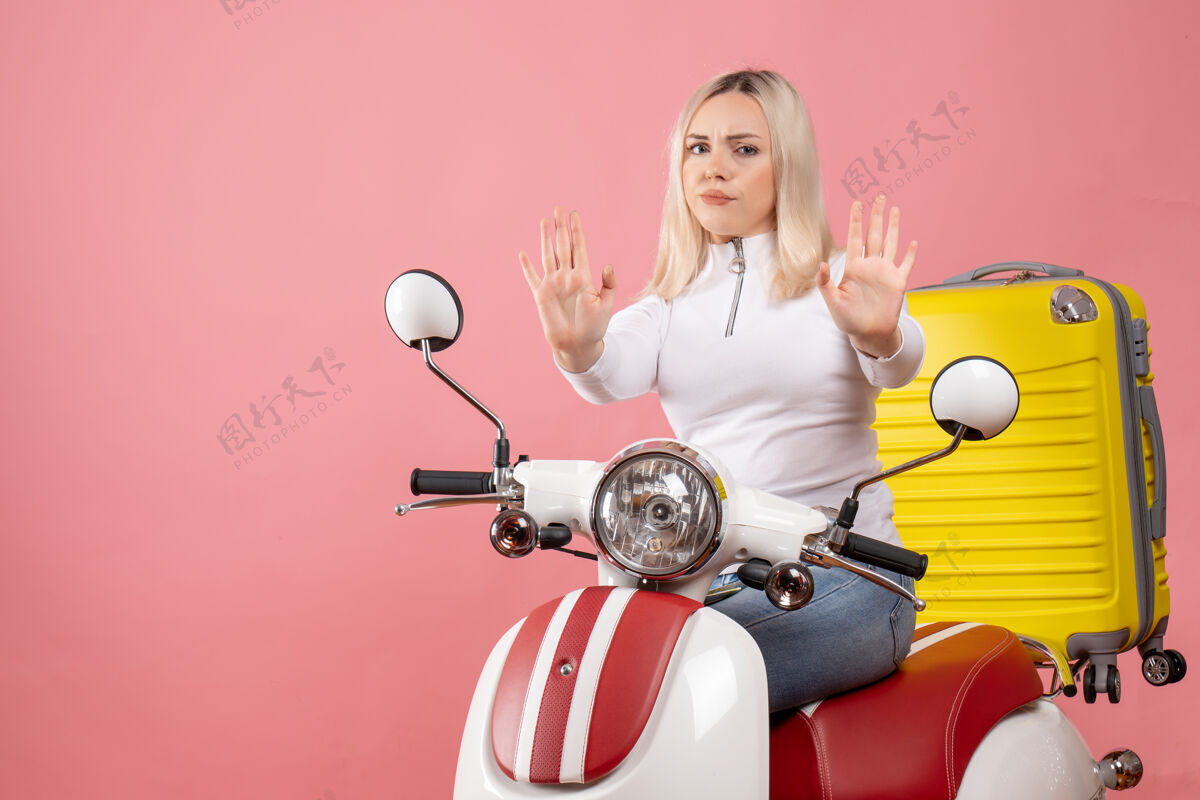 微笑前视图不满的年轻女士在轻便摩托车上做停车标志成人停坐