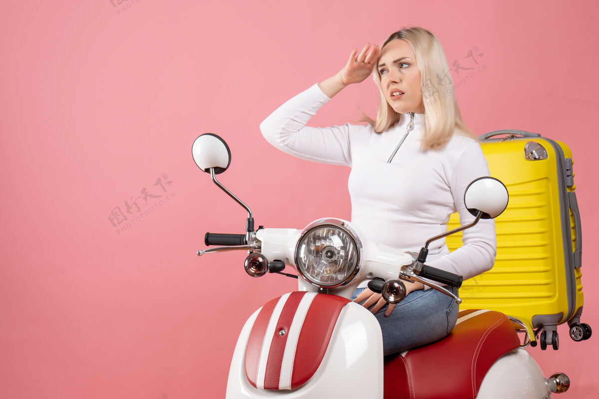 摩托车前视图不满的年轻女士坐在轻便摩托车上观察成人车辆运动