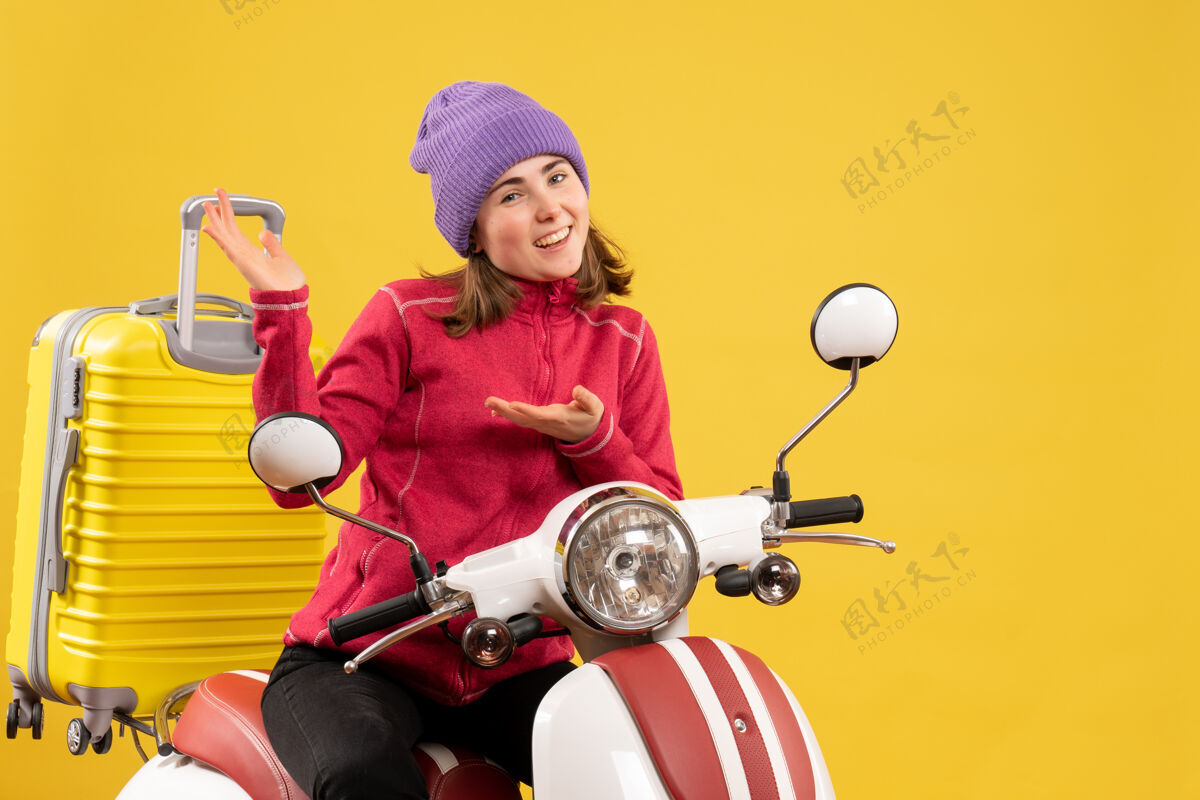 传送带正面图骑着轻便摩托车的快乐的年轻女子指着什么东西前面人男性