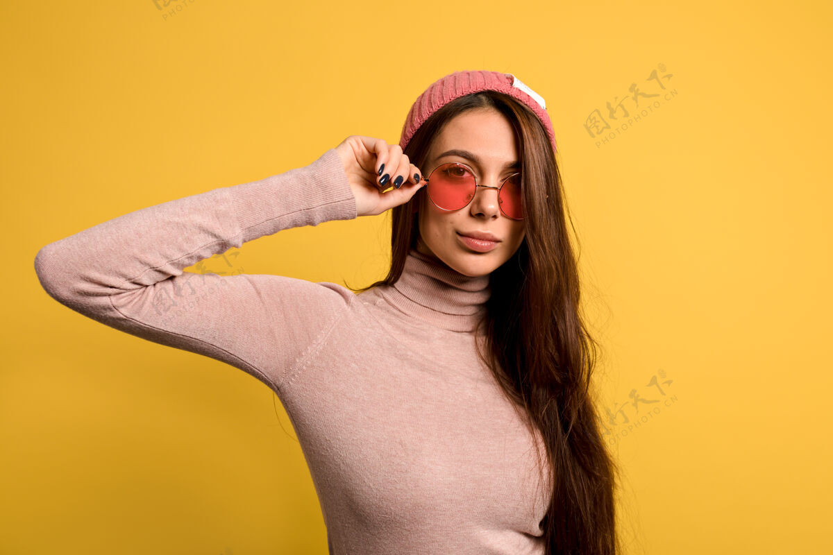 姿态时尚的现代女性 长直发 穿着粉色衬衫 戴着粉色帽子 戴着粉色圆眼镜 面带微笑态度表达表情