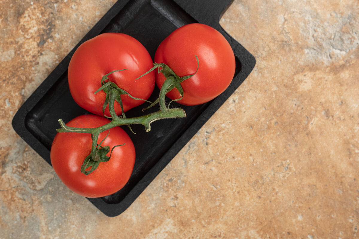 美味一堆新鲜的 红色的西红柿和绿色的茎放在深色的盘子里熟的生的营养