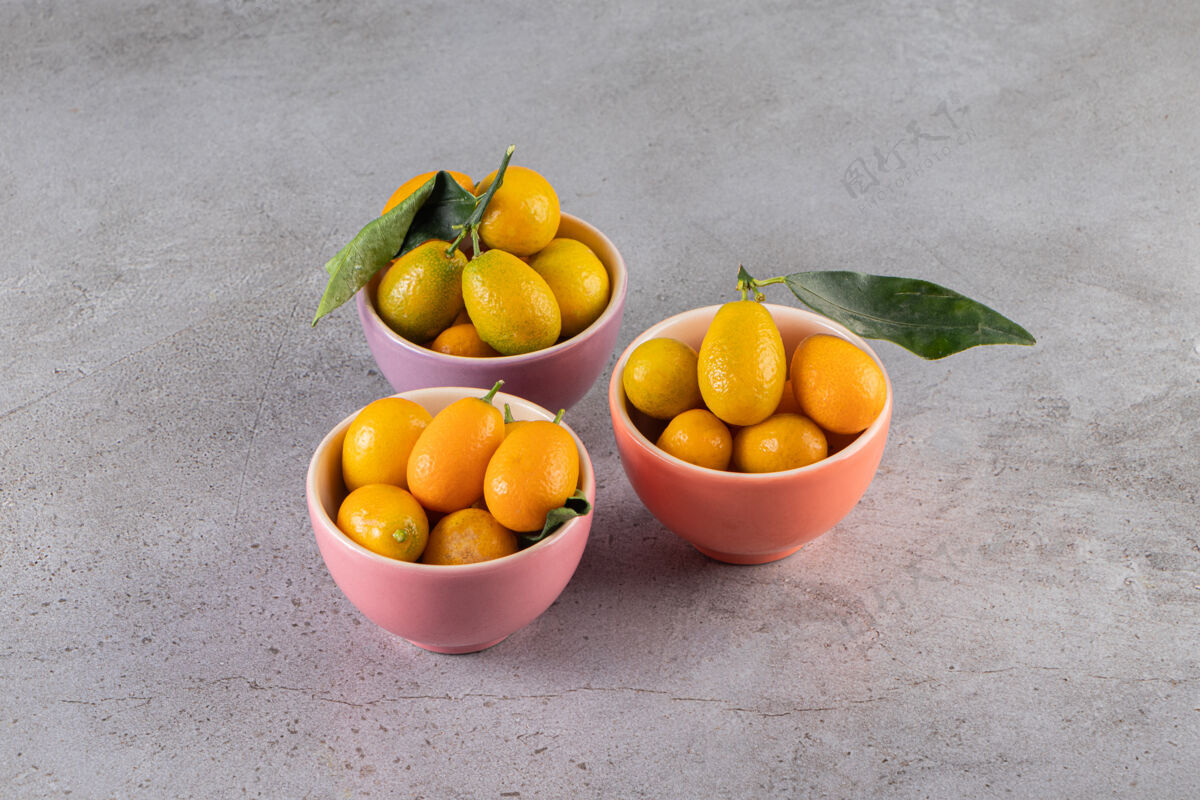 有机五颜六色的碗新鲜多汁的金橘在石头表面多汁膳食异国情调