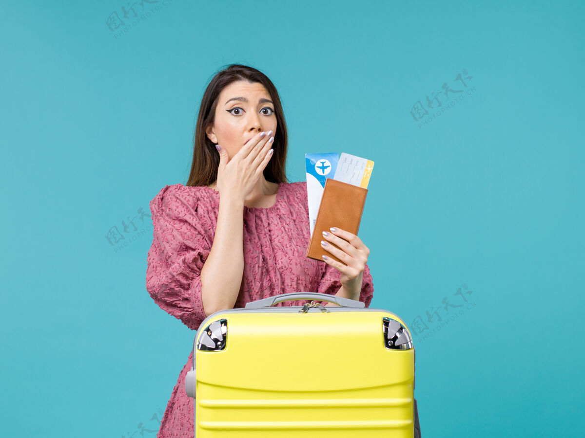 举行前景度假中的女性拿着她的票在淡蓝色的背景下旅行度假的女人夏天的海惊喜微笑嘴