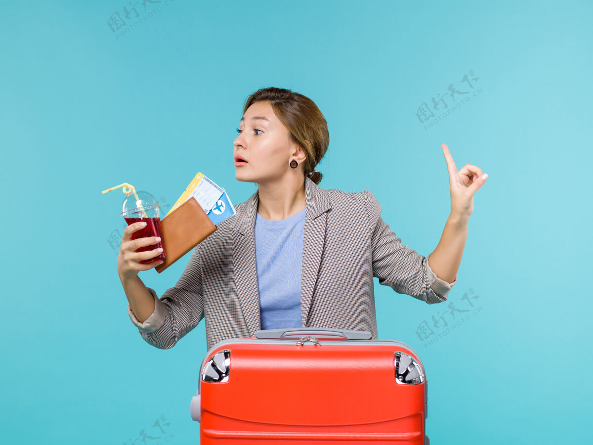 肖像前景度假中的女性拿着果汁和浅蓝色背景的机票旅行度假海上飞机票女人果汁