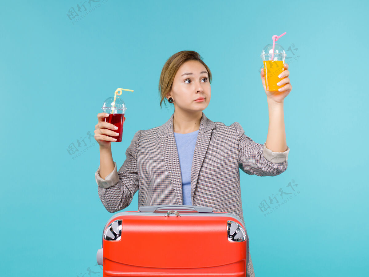 成人前视图：度假中的女性手持新鲜饮料乘坐蓝色背景的旅行度假海上飞机旅行女人观点