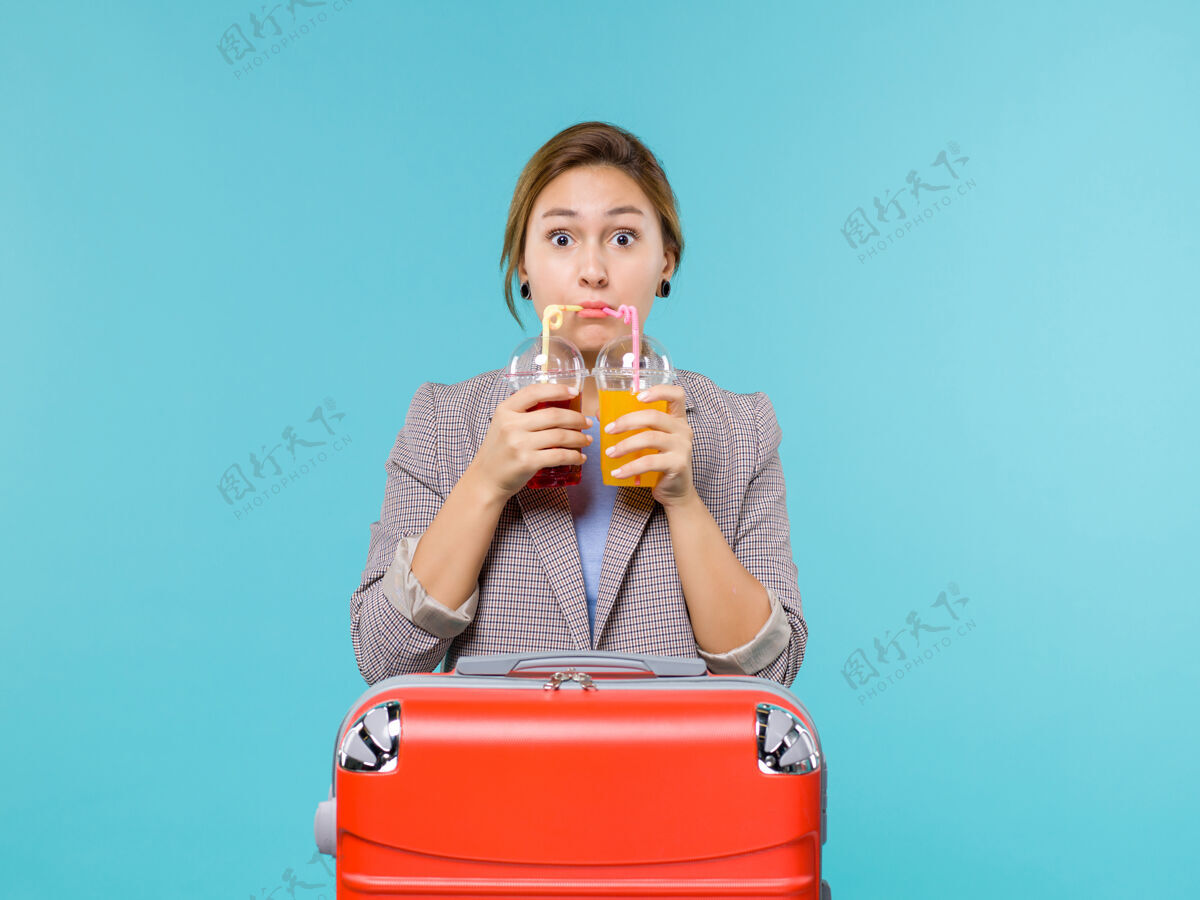 假期前视图：度假中的女性手持新鲜饮料乘坐蓝色背景的海上旅行度假飞机航行人前面