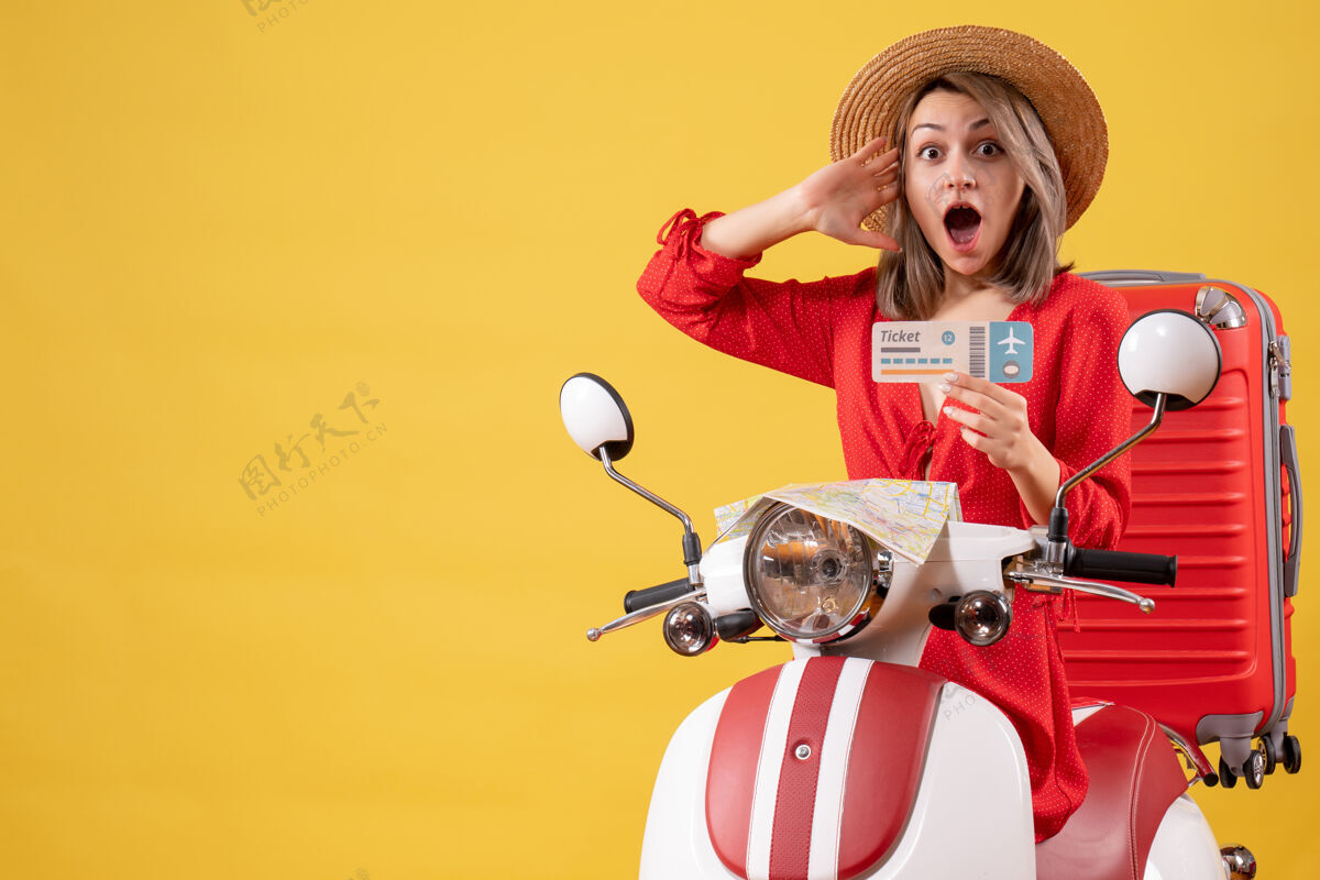 举行一位穿着红裙子的年轻女士手持轻便摩托车的车票 眼前一亮运动轻便摩托车乐趣