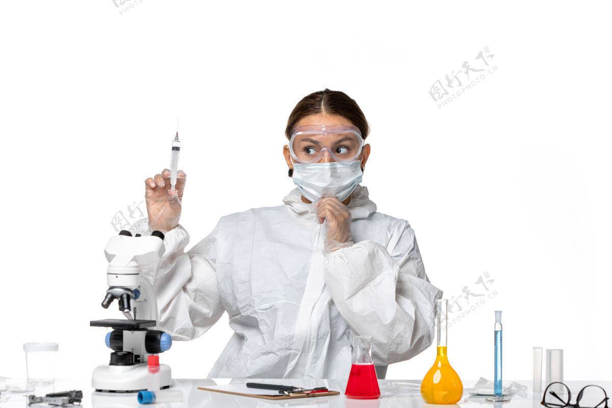 女医生正面图女医生穿着防护服 戴着口罩拿着注射用的白色办公桌病毒药柯维德大流行人医生病毒