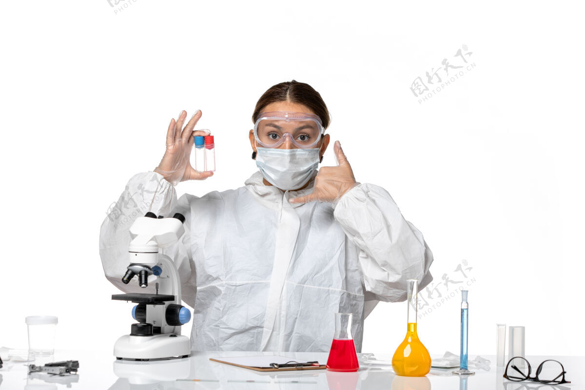 大流行正面图：穿着防护服 戴着口罩的女医生拿着白色背景的空烧瓶 身上有冠状病毒外套病毒空