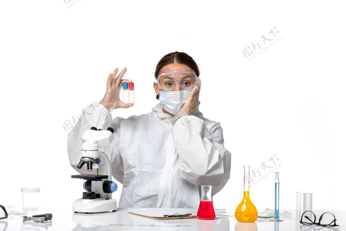 医疗正面图：穿着防护服 戴着口罩的女医生拿着空烧瓶 背景是白色的冠状病毒白人正面面罩