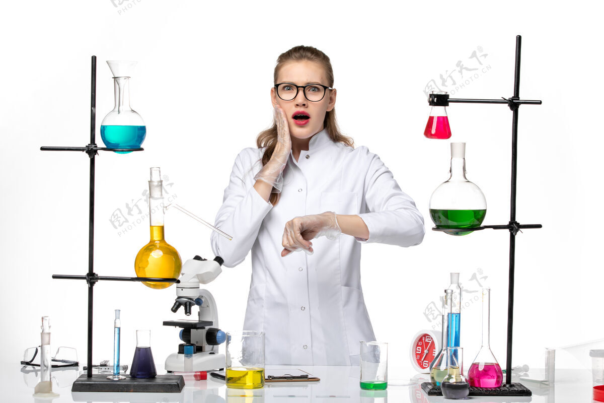 医学前视图穿着医疗服的女化学家在白色背景上看着自己的手腕化学大流行的冠状病毒检查健康白人