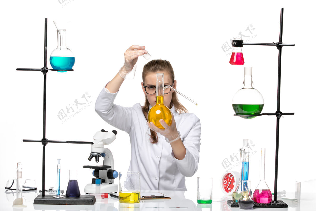 白前视图穿着医疗服的女化学家拿着白色背景上黄色溶液的烧瓶化学大流行性冠状病毒实验室医学化学