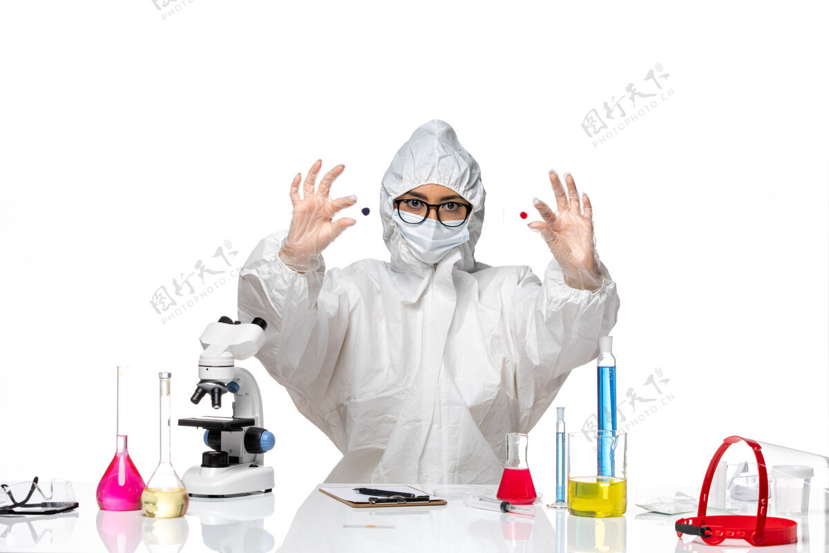 医生正面图：穿着特殊防护服的女化学家拿着样品放在白色办公桌上病毒化学可以预防大流行健康前面病毒外套
