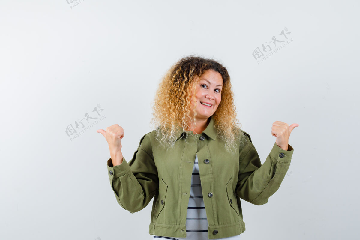 护理一个金发卷曲的女人 穿着绿色夹克 用大拇指指向相反的方向 看起来很快乐 正面视图拇指方向黑发