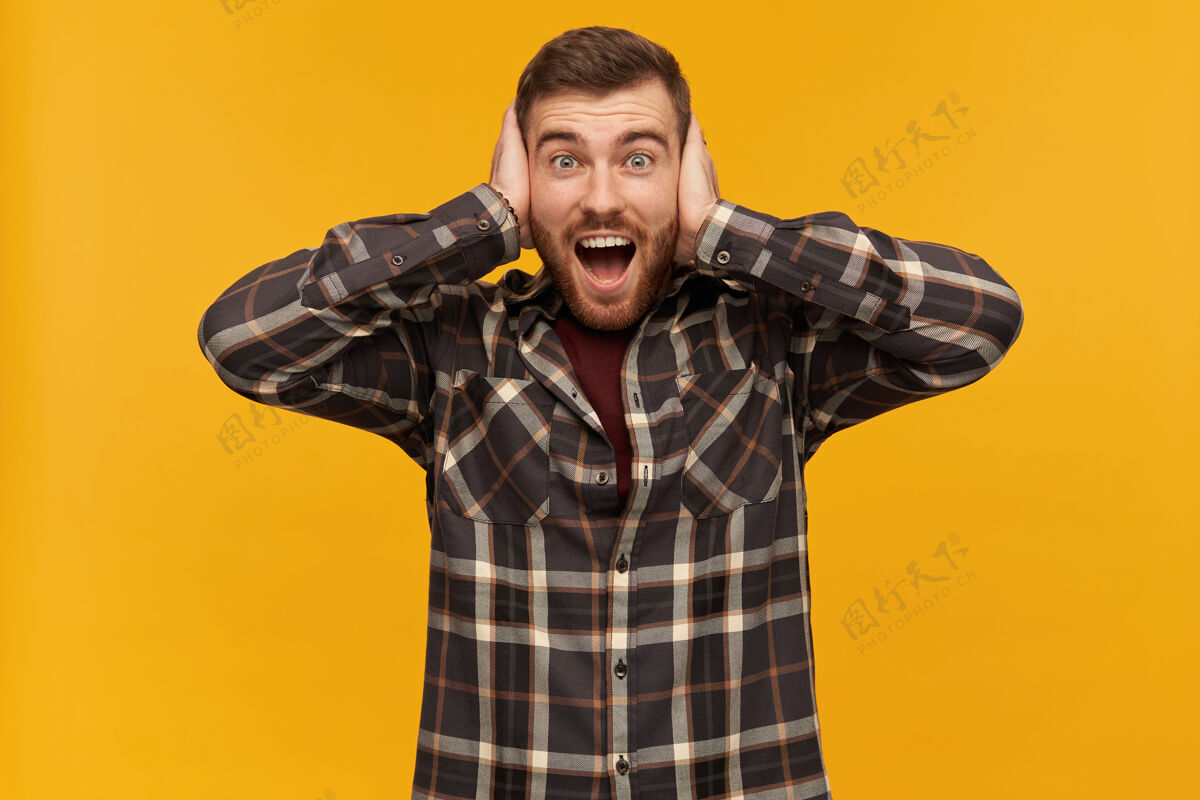 情绪有胡子的男人 快乐的男人 深色头发穿着格子衬衫和配饰情感概念用手掌捂住耳朵 隔离在黄色的墙上欧洲人帅气男性