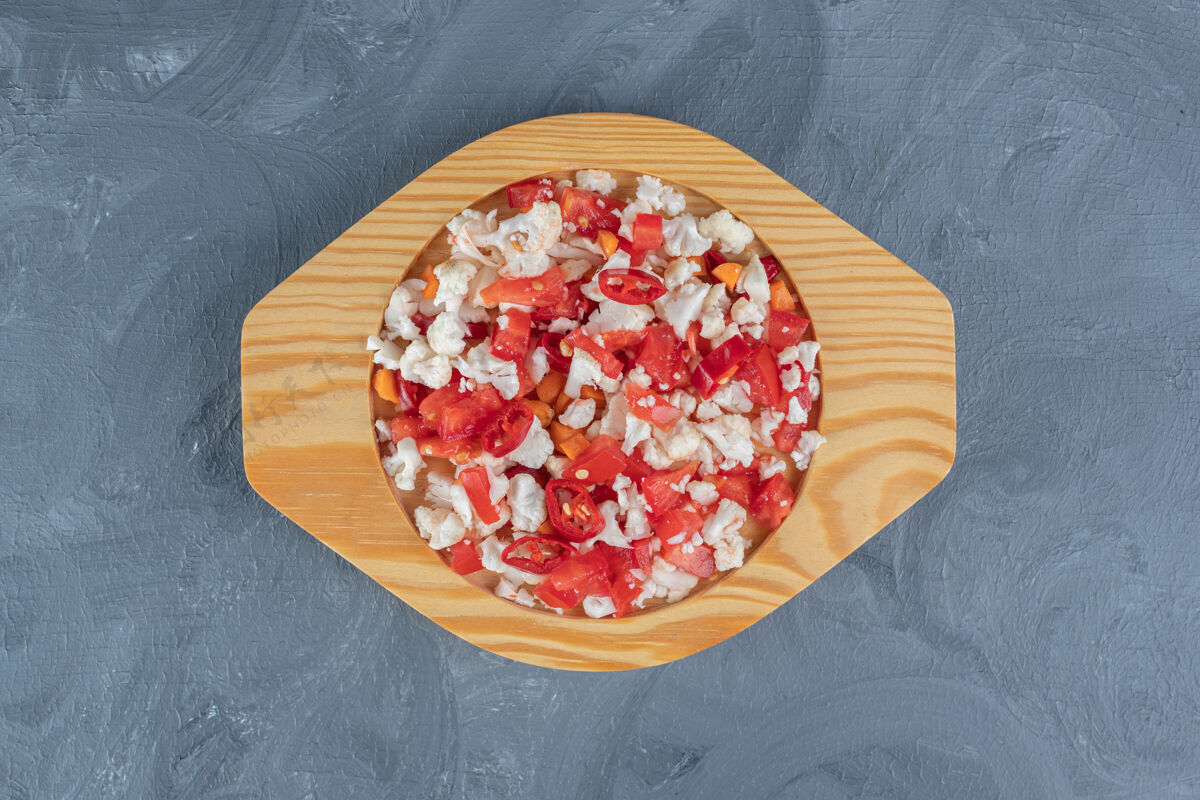 拼盘在大理石桌上的小木盘上放胡椒和花椰菜沙拉美味膳食胡萝卜