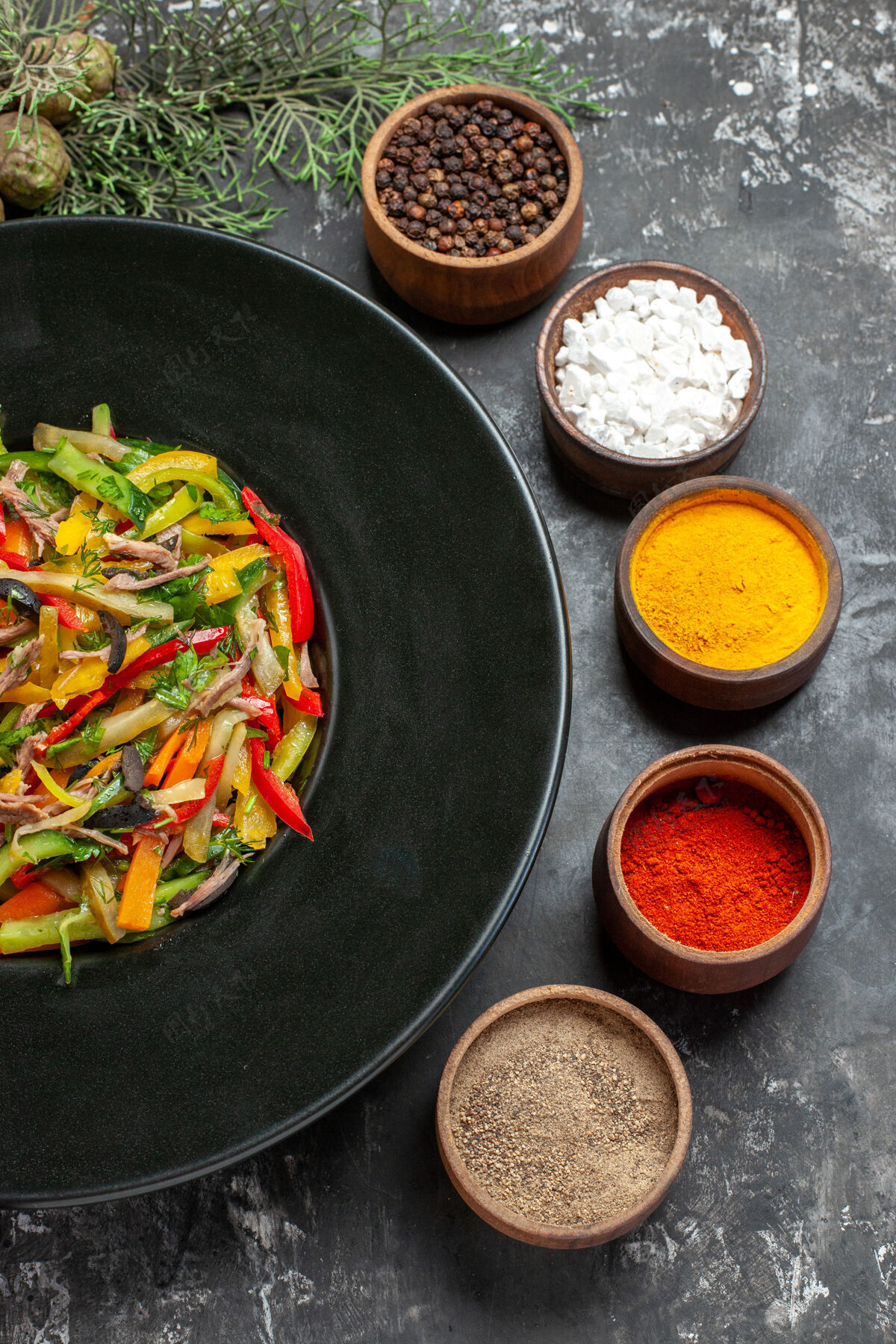 荷兰烤箱黑色表面上美味蔬菜沙拉的俯视图美味蔬菜沙拉调味品胡椒