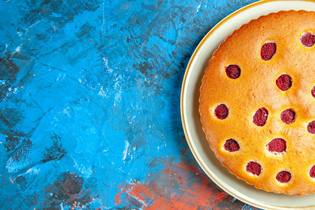 透明蓝色表面上白色椭圆形盘子上草莓蛋糕的俯视图表面泡草莓蛋糕